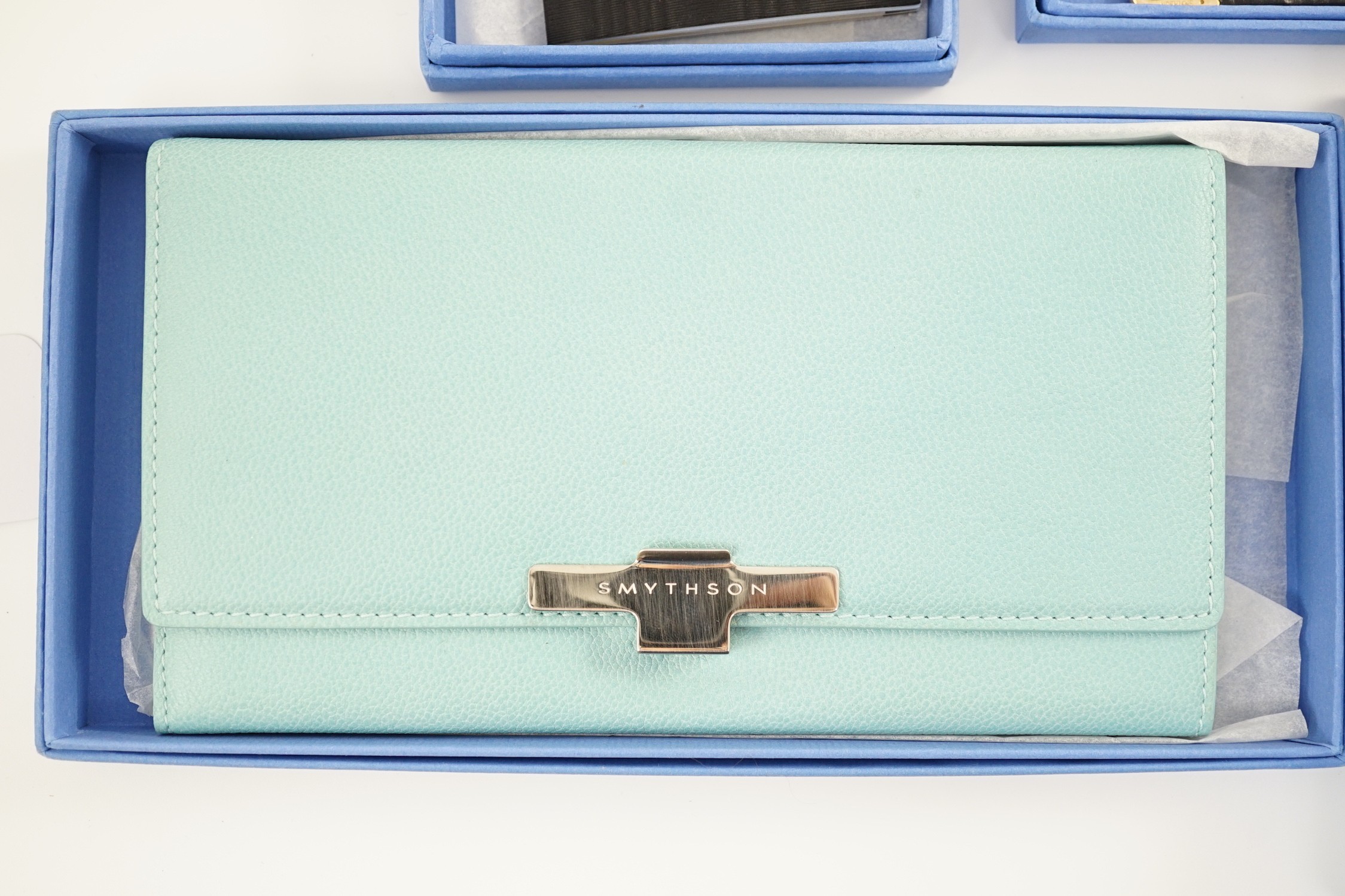 Smythson of London. A black leather notepad, 14cm, two moire silk address/telephone books, a pale grey leather purse,18cm, a Panama cornflower blue notebook, 14 cm and a duck egg blue purse, 20 cm. all boxed.
